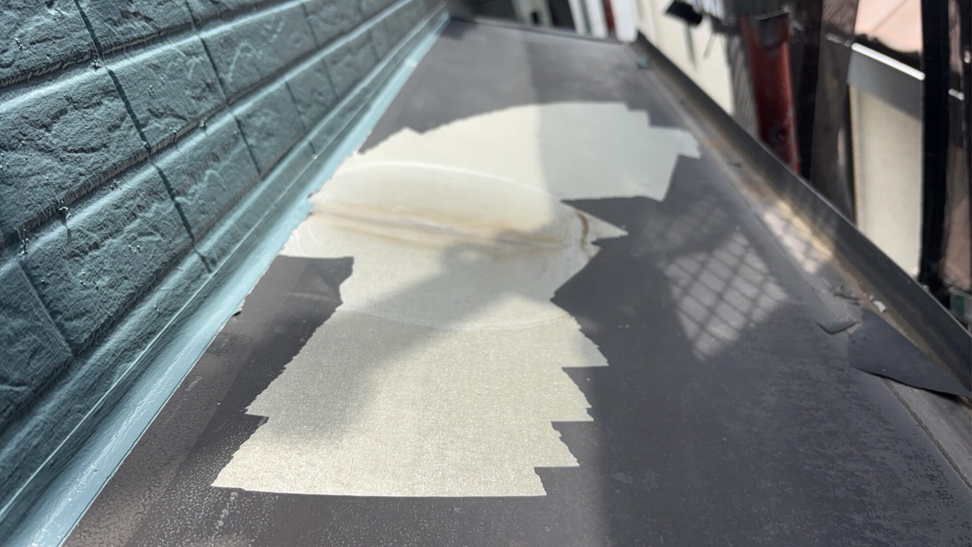 羽村市U様邸で庇板金のケレン清掃を行っている様子