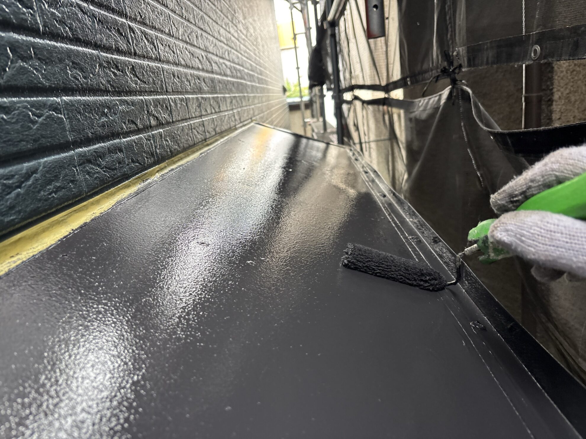 羽村市U様邸で庇板金に上塗りを行っている様子